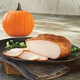 Glazed turkey sliced on a plate beside a pumpkin